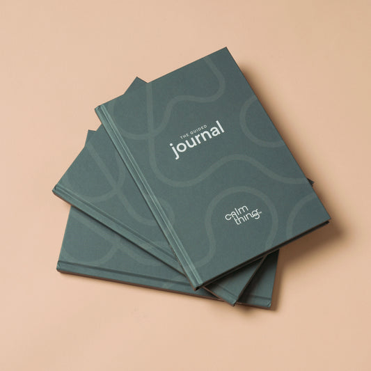 Three forest green journals stacked in a fan shape on a beige background.